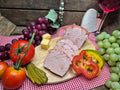 Zwiebelleberkäse auf Holzbrett mit Gemüse